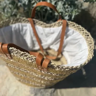 638d3b58f89b6e27b09ceef583446bc34a54356d6562308b9a4056894fb1d08e-1.webp Sequin Basket – Handwoven Doum Palm Fiber Tote with Leather Handles & Drawstring Closure