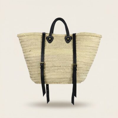 Handwoven Moroccan palm leaf straw market tote with braided leather top handles and convertible leather backpack straps with silver buckles on white surface