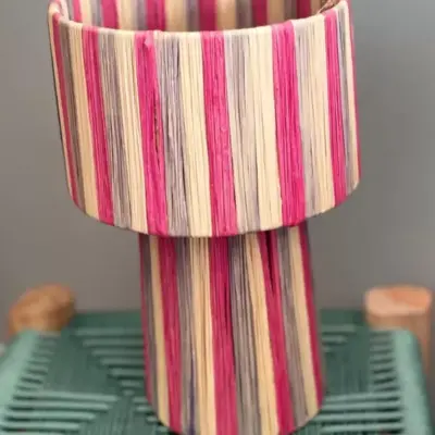 Handmade Moroccan raffia mushroom table lamp with pink grey and natural striped weave on solid square wood base, boho artisan desk light on terrazzo surface