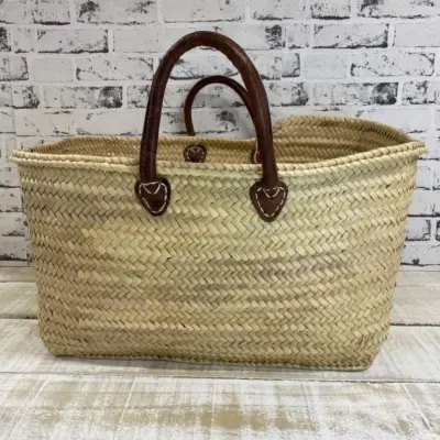 il_794xN.7593299542_t0ud Handmade Moroccan palm leaf straw market basket with short dark leather loop handles and heart-shaped anchor tabs, wide oval open-top silhouette, classic French market style