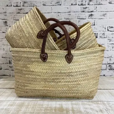 il_794xN.7695510454_kyqr Handmade Moroccan palm leaf straw market basket with short dark leather loop handles and heart-shaped anchor tabs, wide oval open-top silhouette, classic French market style