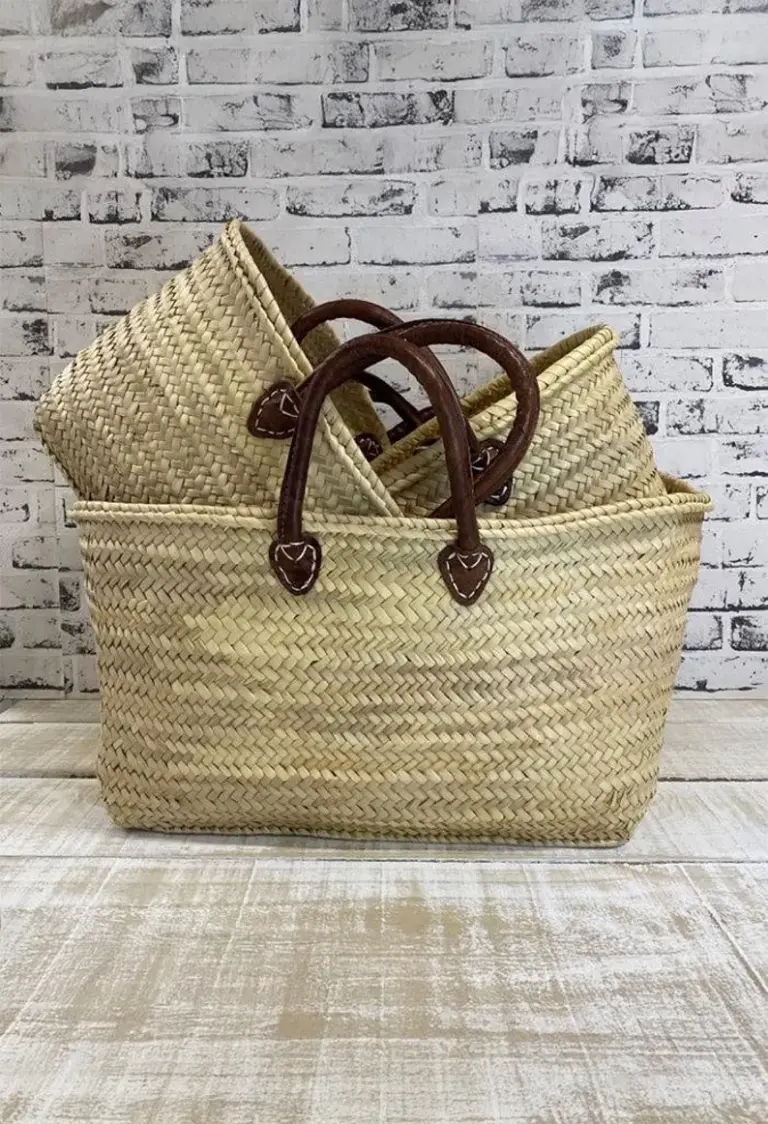 il_794xN.7695510454_kyqr Handmade Moroccan palm leaf straw market basket with short dark leather loop handles and heart-shaped anchor tabs, wide oval open-top silhouette, classic French market style