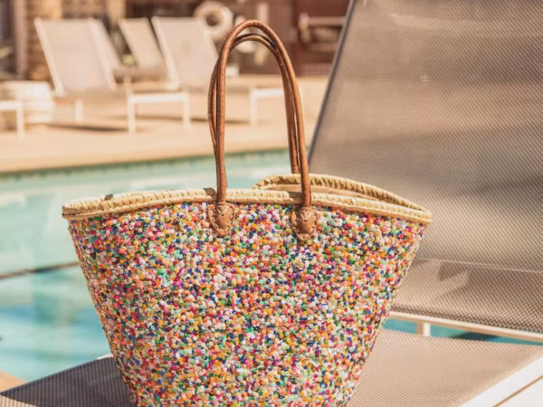 Large handwoven Moroccan straw beach tote bag with all-over multicolor sequin pompom confetti weave, natural braided palm rim, decorative leather anchor tabs and tan leather top handles