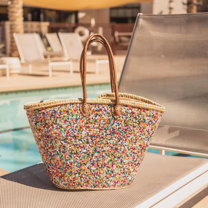 Large handwoven Moroccan straw beach tote bag with all-over multicolor sequin pompom confetti weave, natural braided palm rim, decorative leather anchor tabs and tan leather top handles