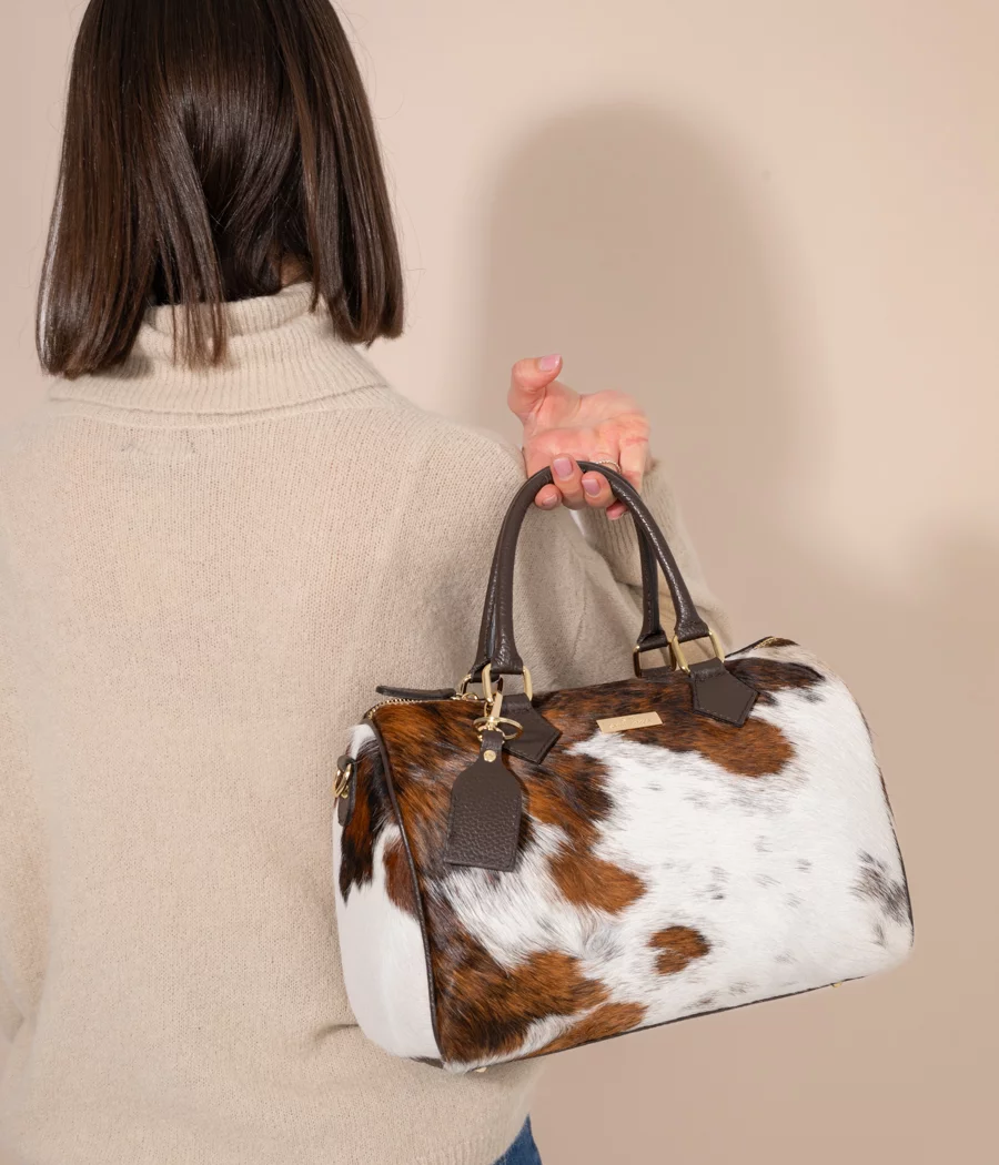 Back view of large cowhide leather barrel bag showing rich brown hair-on-hide texture, western style handbag